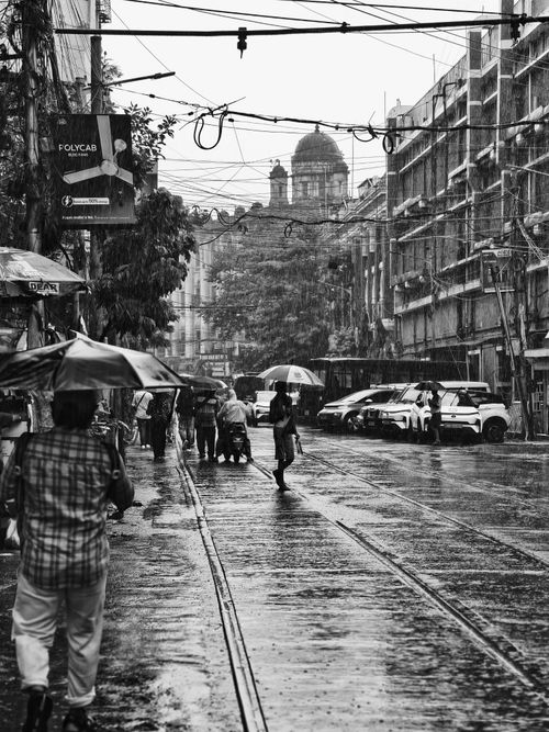 Free Rainy day in Kolkata featuring pedestrians with umbrellas and iconic city architecture. Stock Photo