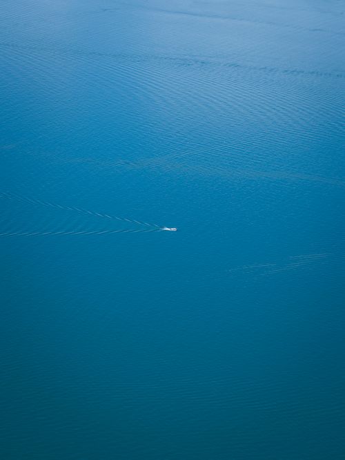 Free A serene aerial shot of a boat moving across the expansive blue ocean, showcasing tranquility and open space. Stock Photo
