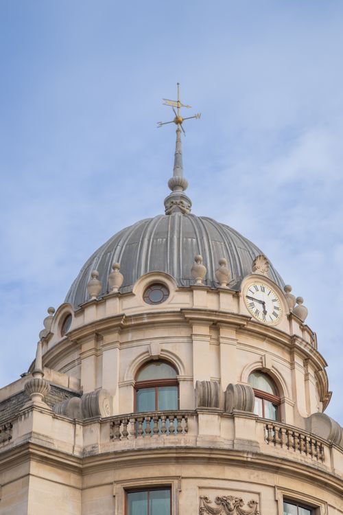 Free A detailed view of a classical dome and clock tower against a blue sky in London, UK. Stock Photo