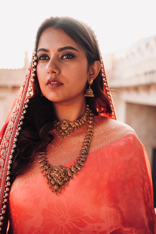 Free Portrait of a woman in a vibrant red sari, showcasing traditional jewelry and cultural elegance. Stock Photo