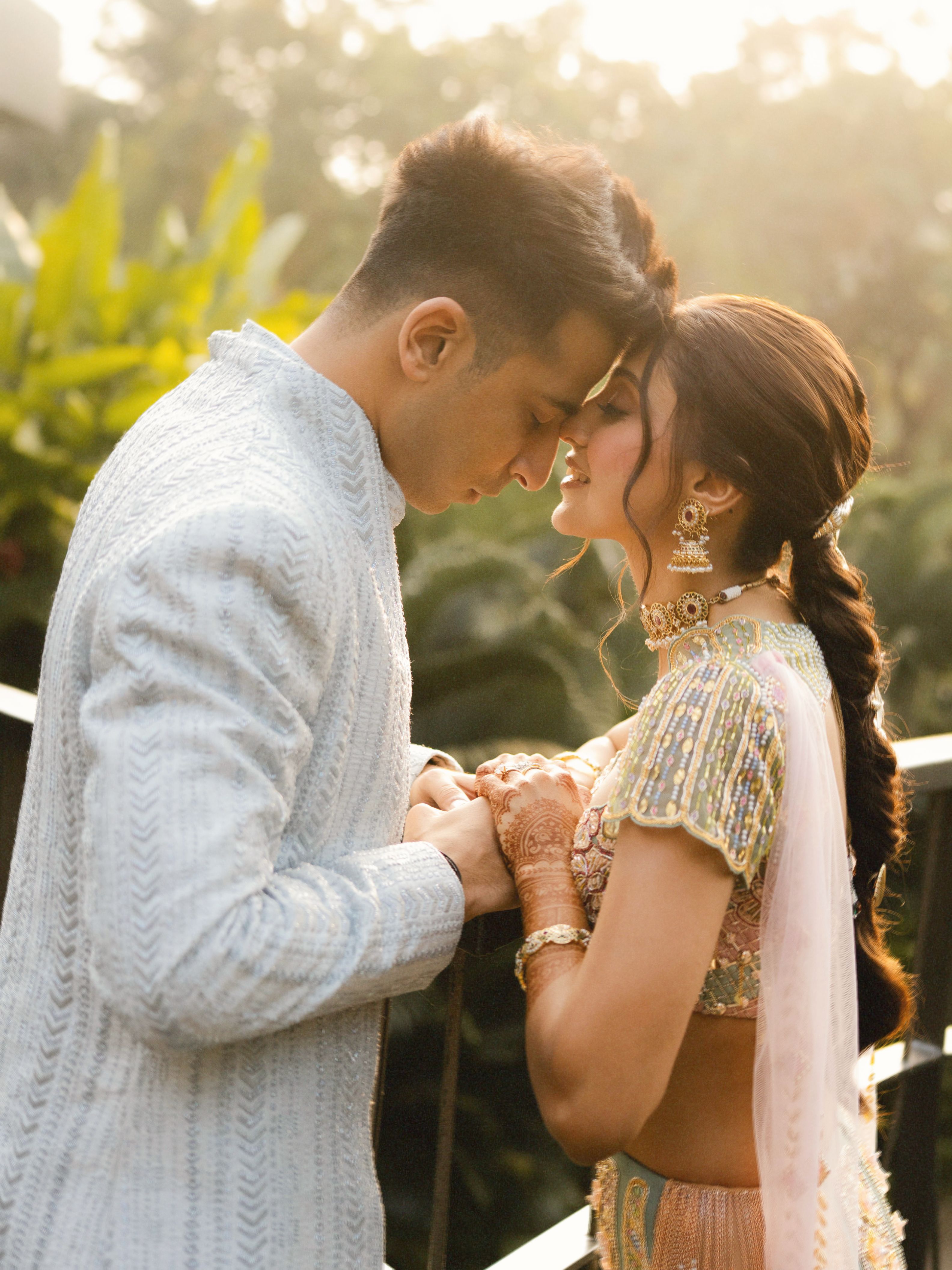 A romantic moment between a couple in traditional attire, captured outdoors with warm lighting.