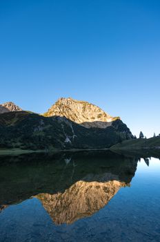 Clear morning view of an alpine mountain reflected in a tranquil lake in Oberstdorf, Germany.