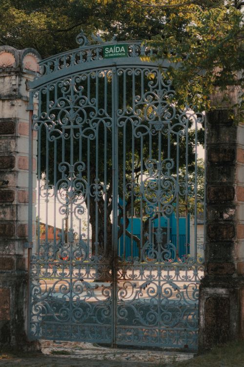 Free Elegant iron gate with intricate design located in Natal, Brazil, featuring a 'SAÍDA' sign. Stock Photo
