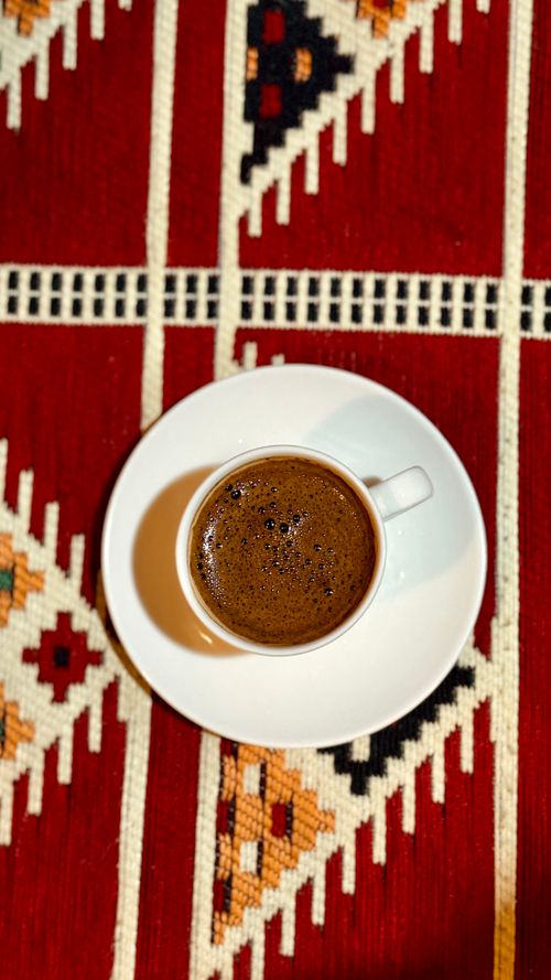 Free A cup of Turkish coffee served on a vibrant patterned rug, showcasing rich cultural textures. Stock Photo
