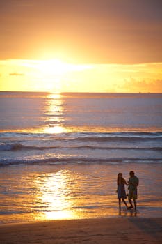 一对夫妇在日落时分沿着海滩宁静地散步，景色令人惊叹