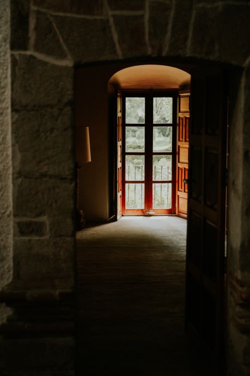 Free Rustic hallway with an open wooden door revealing a sunlit view outside. Stock Photo