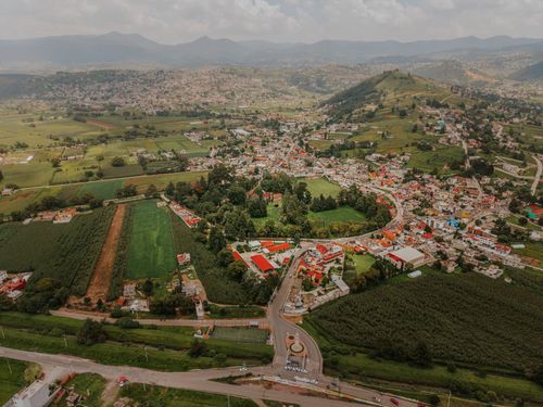 Free Panoramic aerial image of Santiago Tianguistenco with lush green fields and distant mountains. Stock Photo