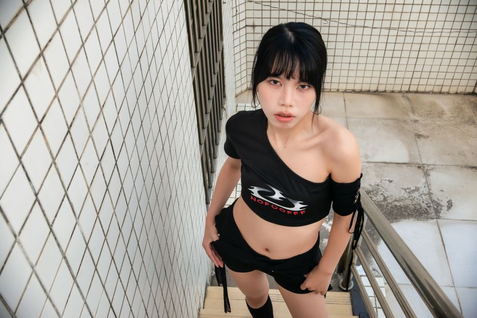 おしゃれな服装をした、流行に敏感な若い女性が、屋外のタイル張りの階段に立っている。