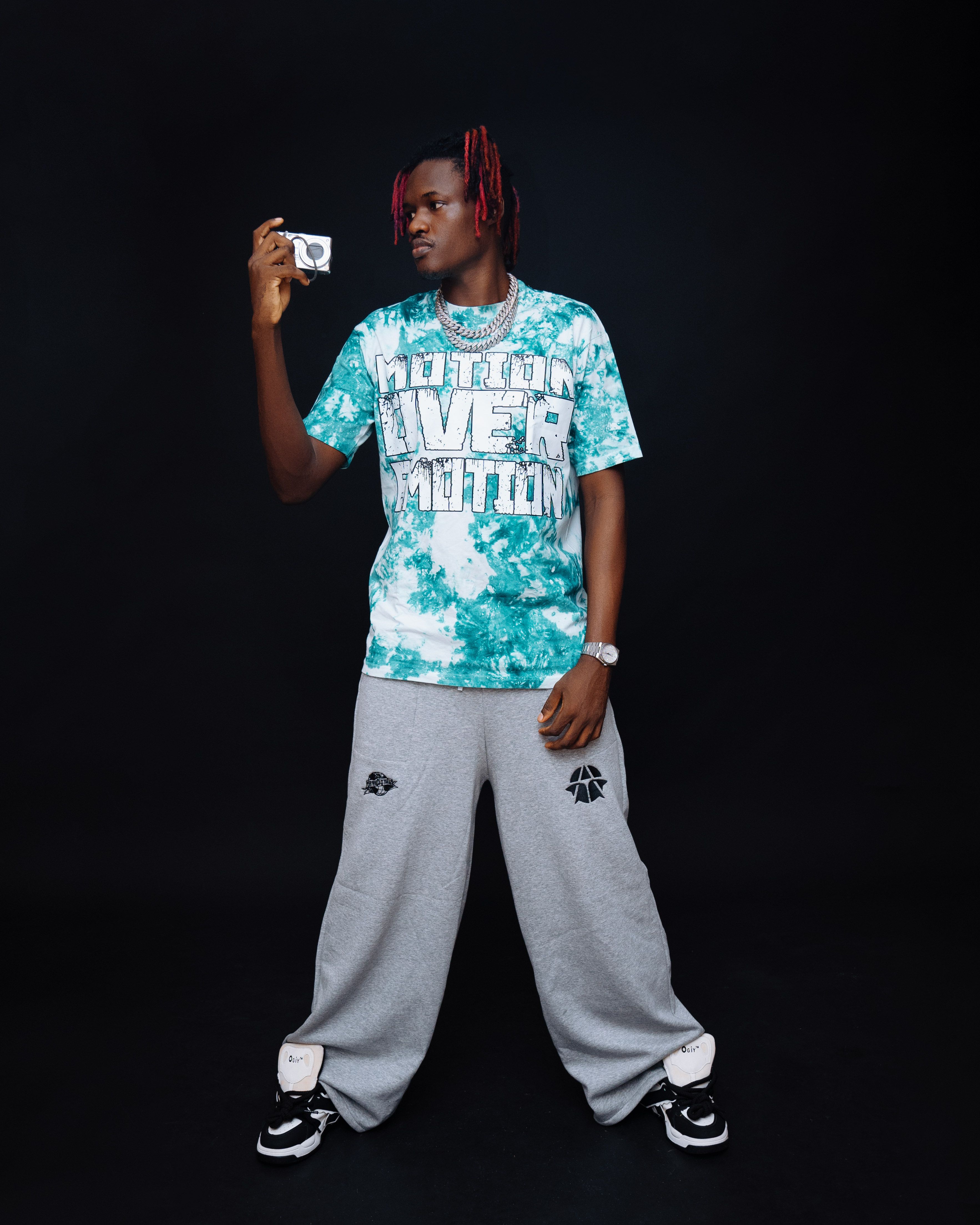 Stylish young man holding a vintage camera in a studio setting, showcasing fashion and creativity.