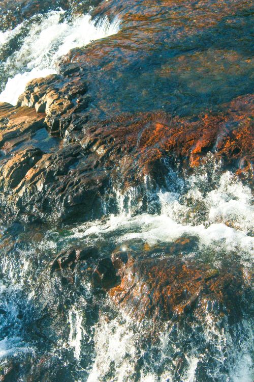 Free Flowing waterfall over textured rocks, creating a serene natural scene. Stock Photo