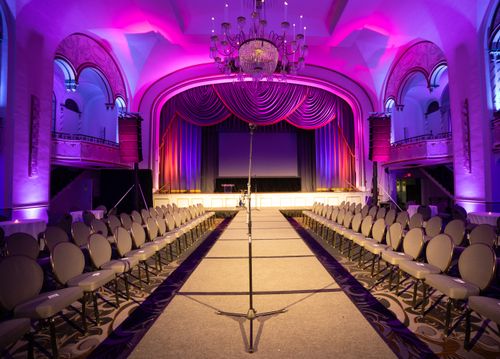 Free Lavish auditorium setup with a central runway and grand chandelier, ideal for fashion shows or events. Stock Photo