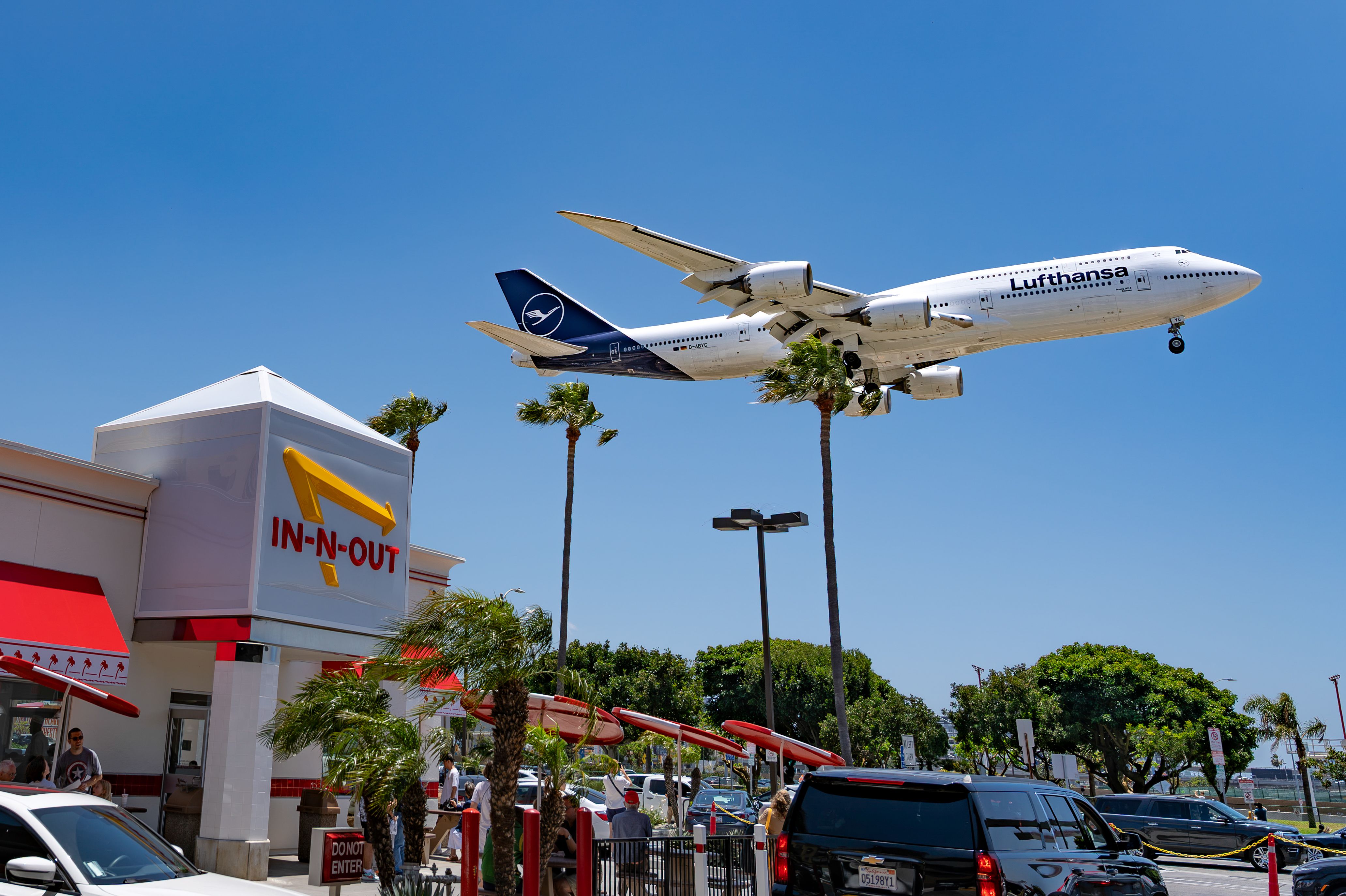 A Lufthansa plane descends over an In-N-Out Burger near LAX in Los Angeles, California.