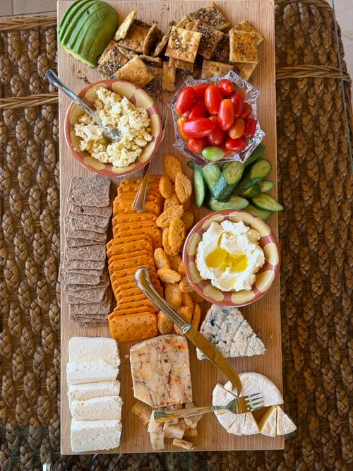 Free A vibrant cheese and snack platter featuring an assortment of cheeses, vegetables, and crackers on a wooden board. Stock Photo
