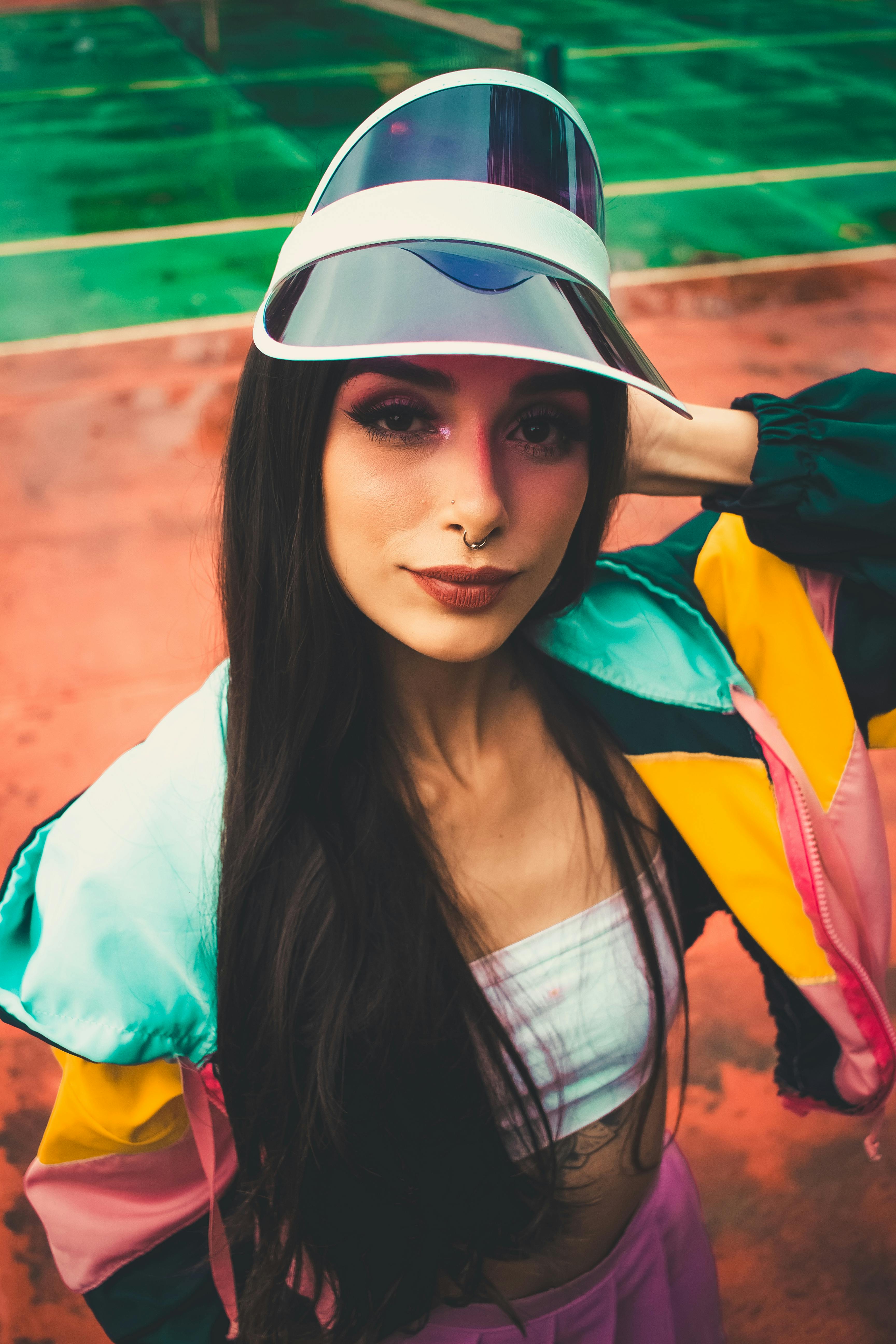 Fashionable woman posing on a tennis court in vibrant athletic attire, showcasing modern style.