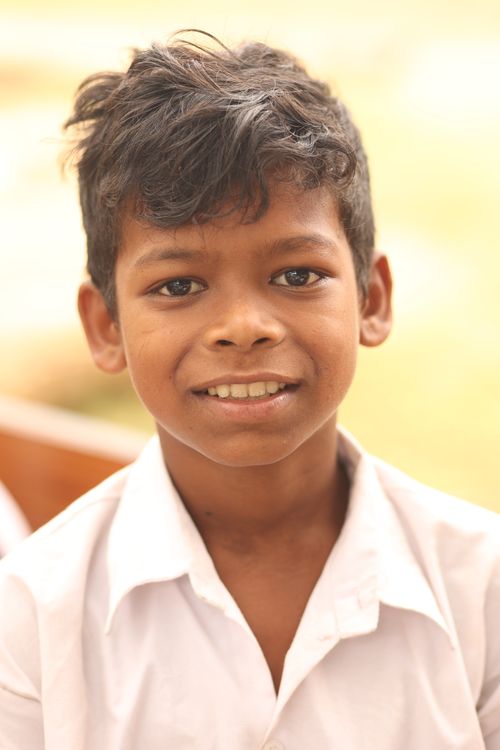 Free Close-up portrait of a happy young boy outdoors, wearing a white shirt. Stock Photo