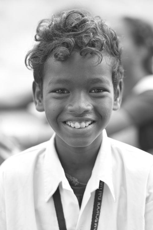 Free Black and white portrait of a smiling child with curly hair wearing a white shirt. Stock Photo