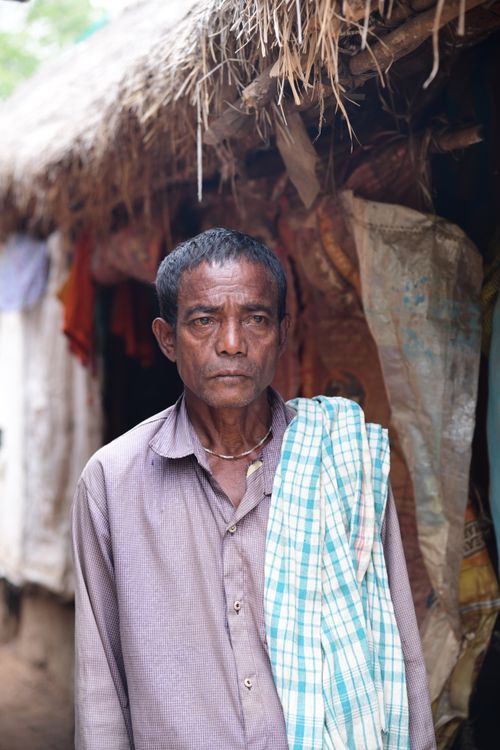 Free A portrait of a South Asian man standing outside a traditional rural hut in Bhubaneswar, Odisha. Stock Photo