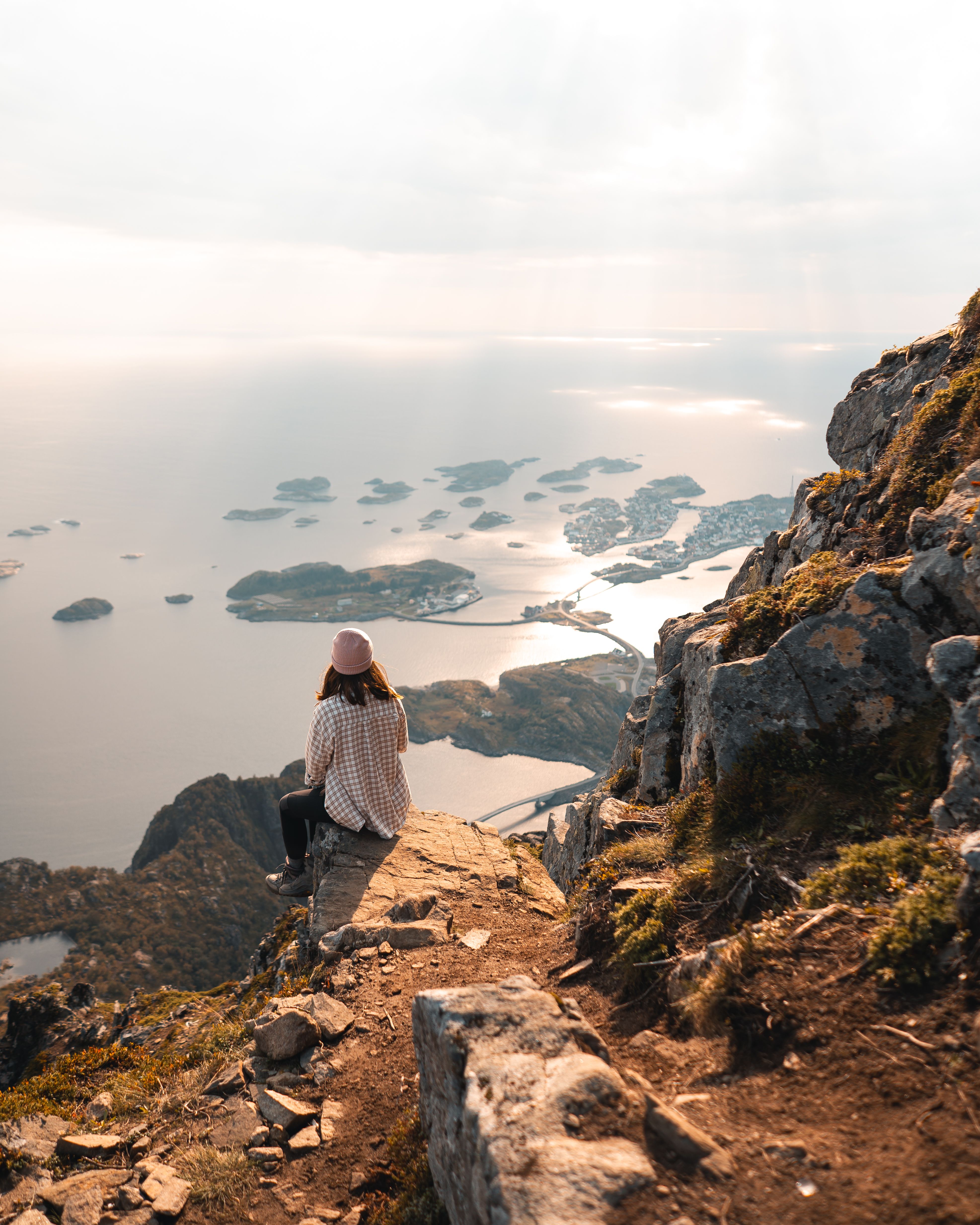 Woman overlooking stunning Norwegian fjords at sunrise, embracing nature's serenity.