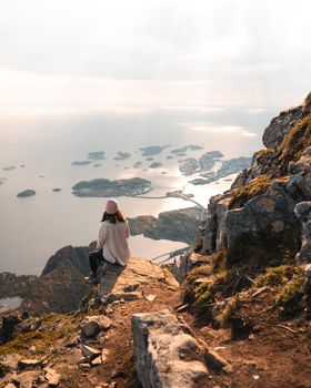 Woman overlooking stunning Norwegian fjords at sunrise, embracing nature's serenity.