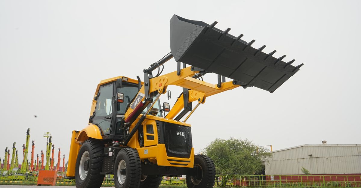 ACE backhoe loader with raised shovel against industrial background in Faridabad.