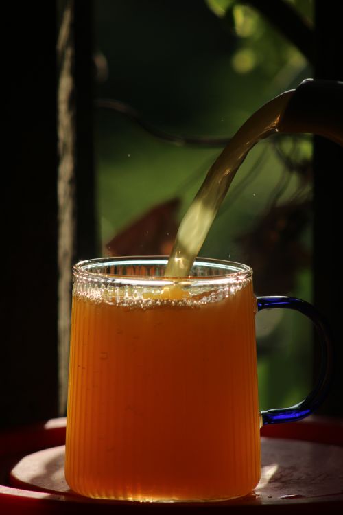 Free Vibrant orange juice being poured into a glass mug with natural light and rustic background. Stock Photo