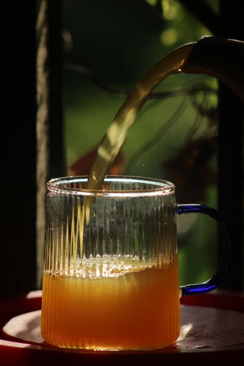 Free Close-up of orange juice being poured into a glass mug with handle outdoors. Stock Photo
