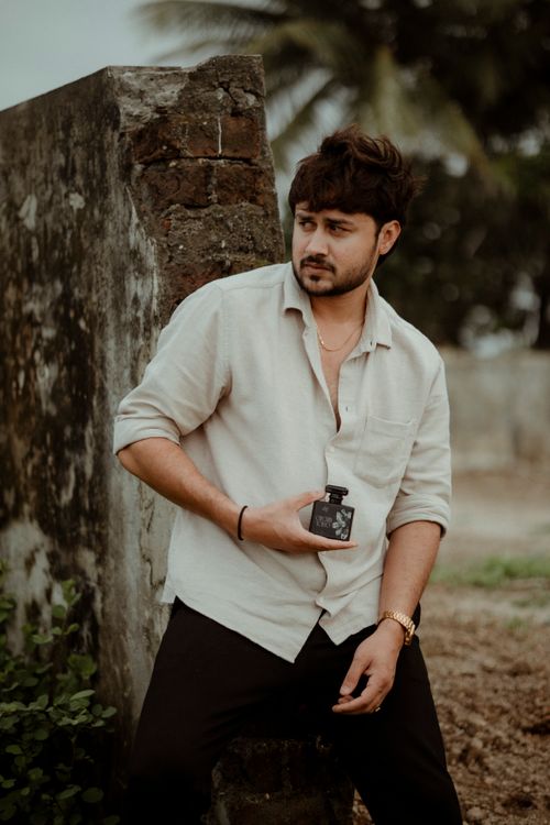 Free Man poses outdoors against a rustic wall in Surat, India, embodying a casual chic style. Stock Photo