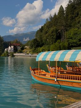Traditional wooden boat moored by the picturesque Lake Bled in Slovenia, surrounded by lush greenery.