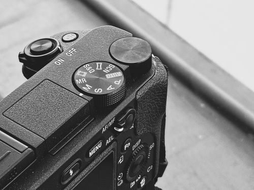 Free Black and white shot of a DSLR camera mode dial with buttons and texture. Stock Photo