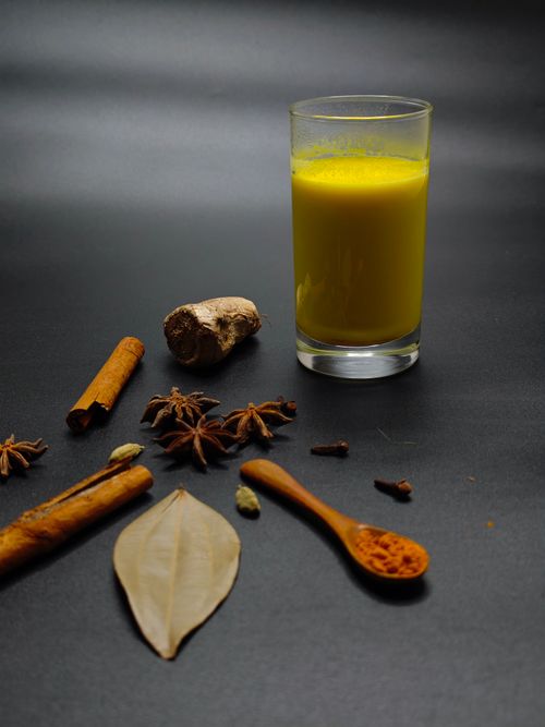 Free A vibrant glass of turmeric milk with a variety of spices on a dark surface, highlighting health benefits. Stock Photo