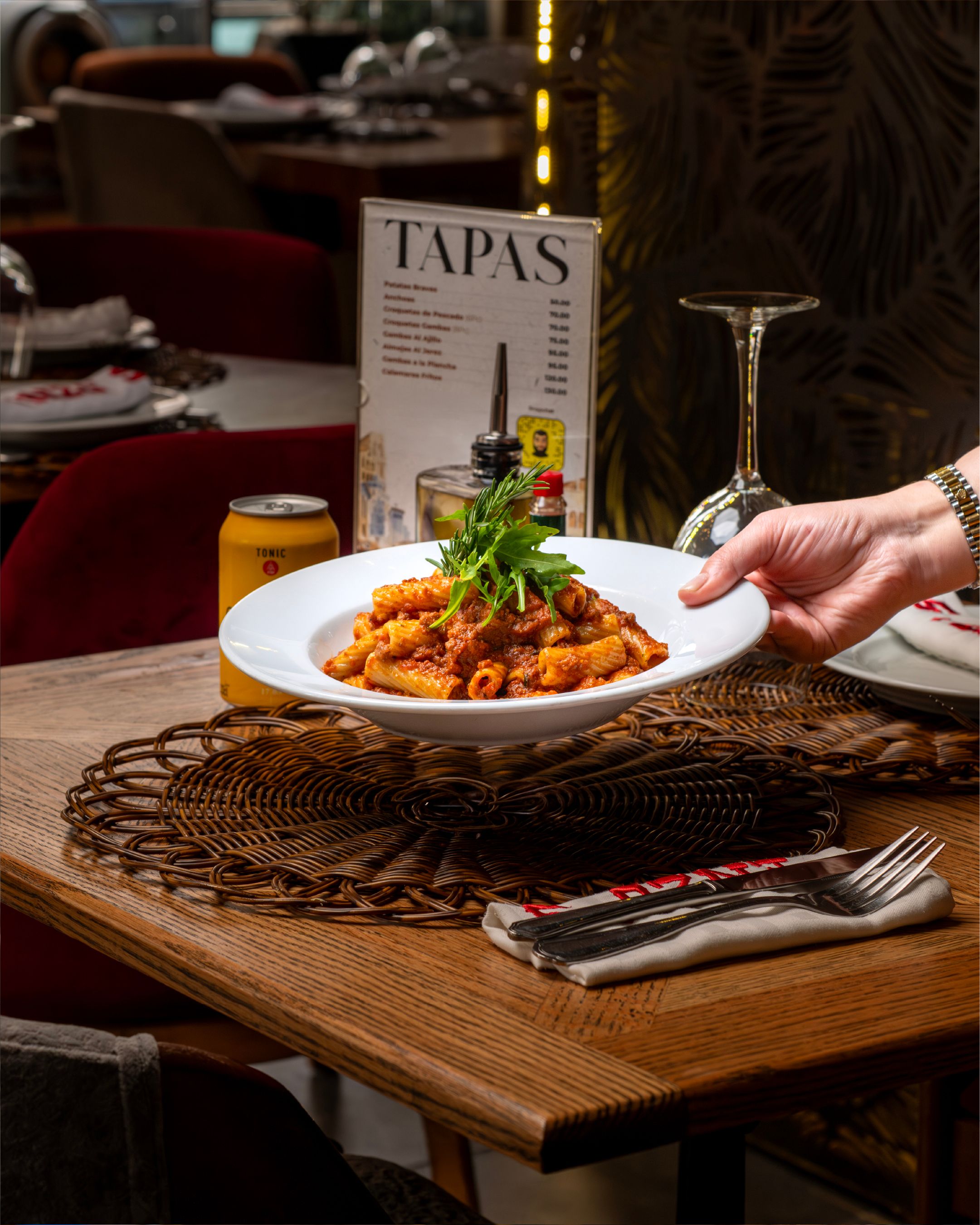 A plate of appetizing pasta being served in a beautifully set restaurant environment.