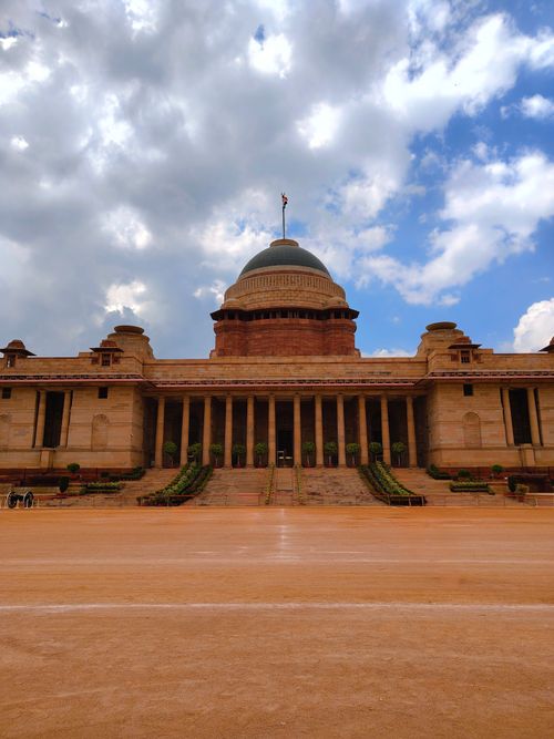 Free Majestic view of Rashtrapati Bhavan, New Delhi, beneath a dramatic cloud-filled sky, showcasing its architectural grandeur. Stock Photo