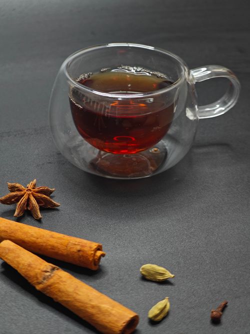 Free A warm glass of spiced tea with aromatic cinnamon and star anise on a dark surface. Stock Photo