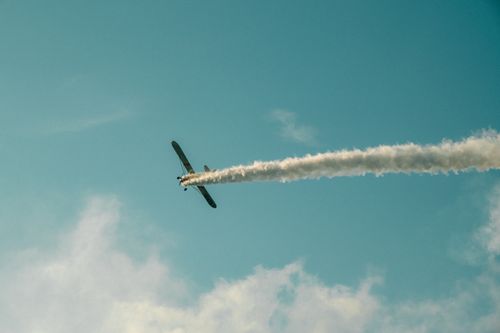 Free A small airplane leaves a trail of smoke as it performs an aerobatic maneuver against a clear blue sky. Stock Photo