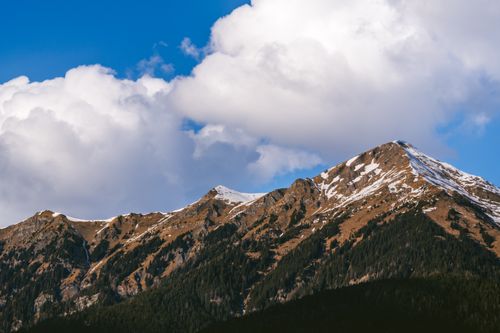 Free Stunning view of the Austrian Alps with snowy peaks and fluffy clouds under a blue sky. Stock Photo
