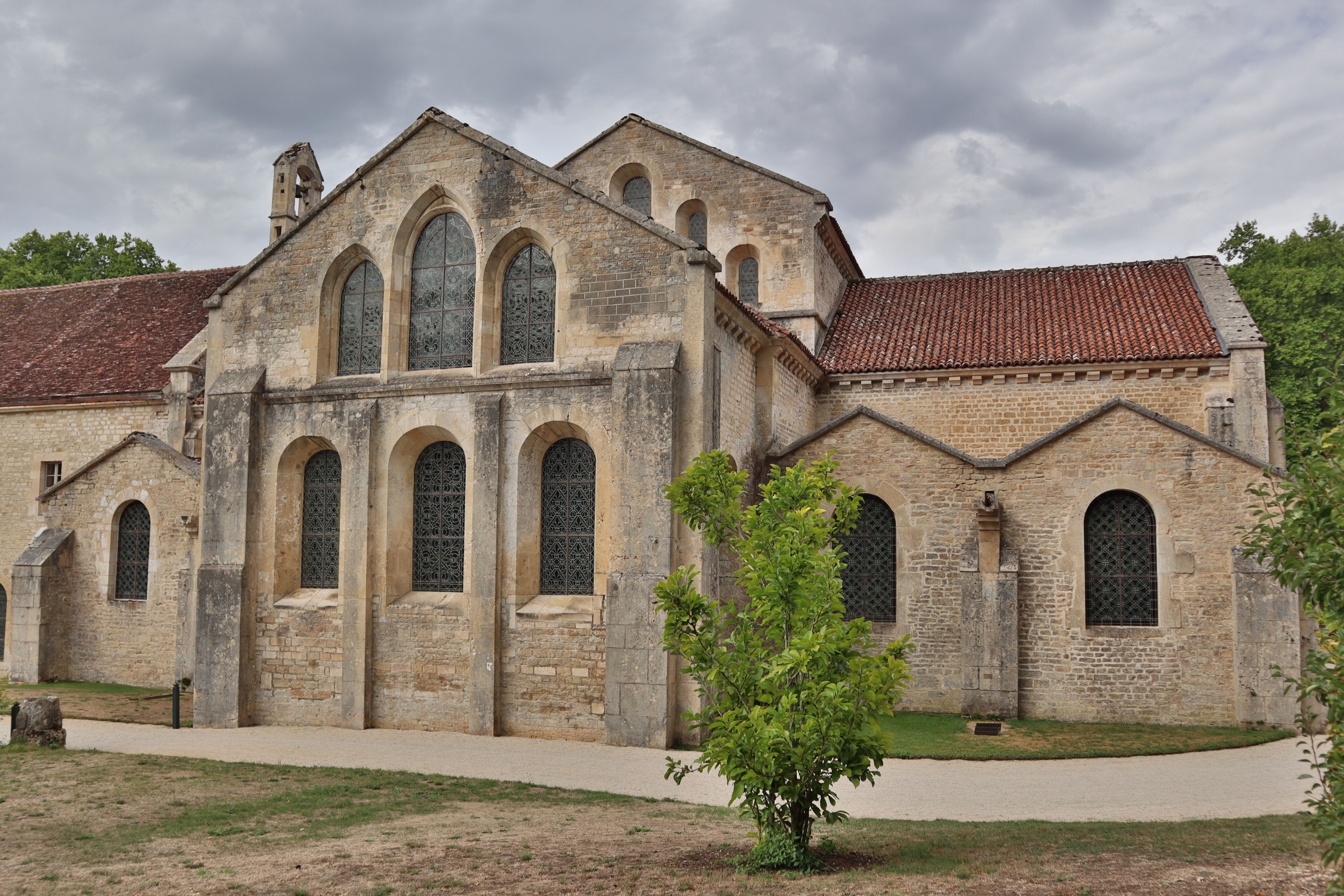 A serene view of the historic abbey church in Montbard, France under a cloudy sky.