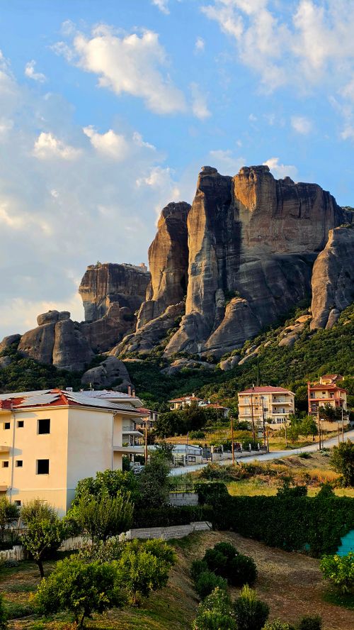 Free Scenic view of Meteora rock formations with village houses in the foreground during sunset. Stock Photo