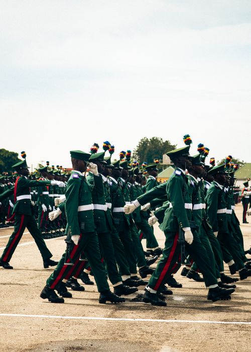 Free Marching soldiers in uniform participate in an outdoor military parade under sunny skies. Stock Photo