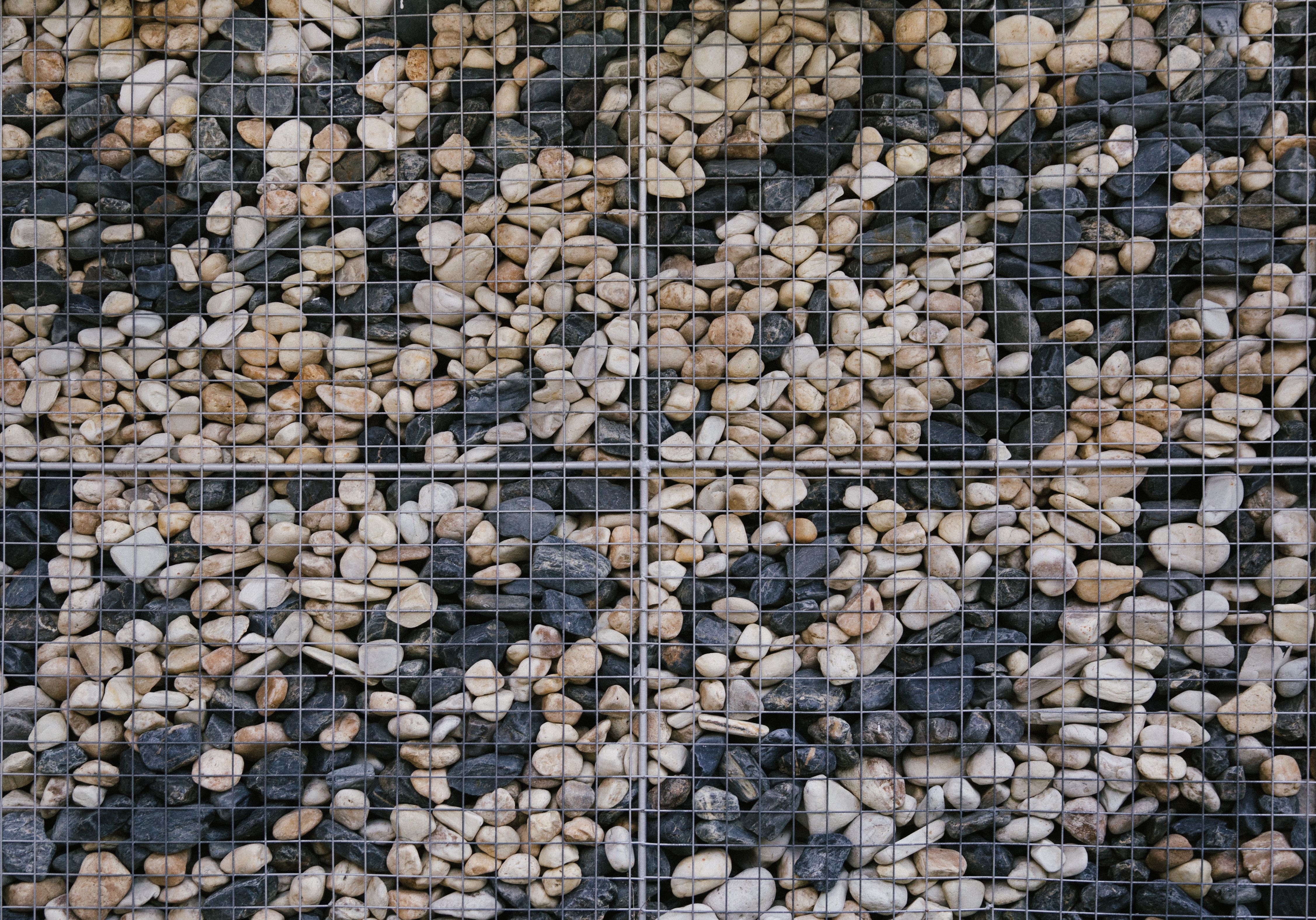 Detailed view of a stone gabion wall showcasing various colored rocks encased in a grid.