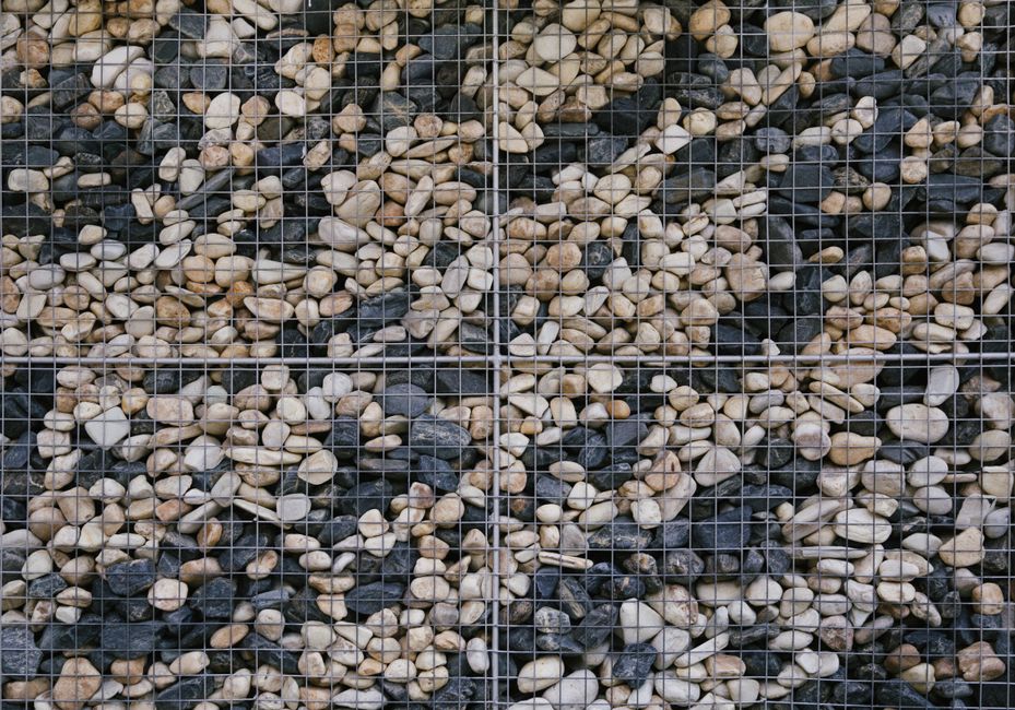 Photo by NEOSiAM 18+ on Pexels Detailed view of a stone gabion wall showcasing various colored rocks encased in a grid.