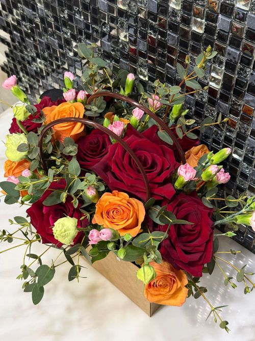 Free A colorful bouquet of red and orange roses with greenery, creating a vibrant floral display. Stock Photo
