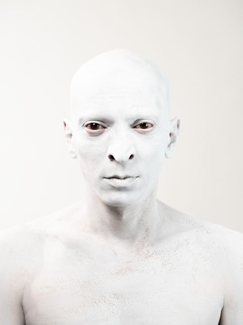Free A striking portrait of a man with white paint on his face, conveying a unique artistic expression. Stock Photo