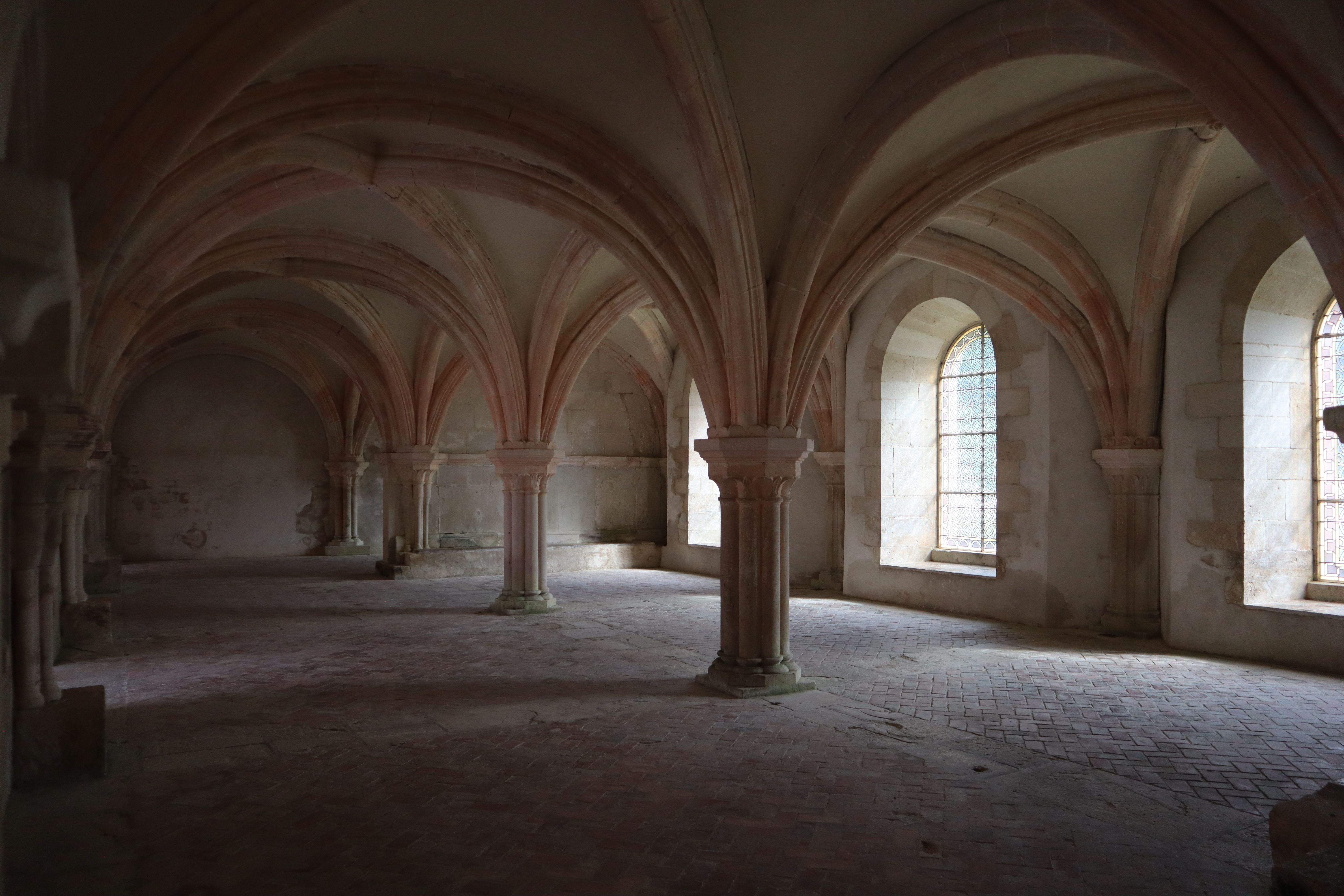 Intricate Gothic arches in a historic abbey in Montbard, France.