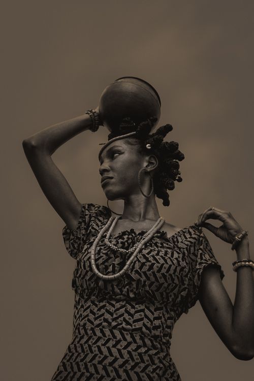 Free Portrait of an African woman in traditional attire carrying a pot on her head, exuding grace and elegance. Stock Photo