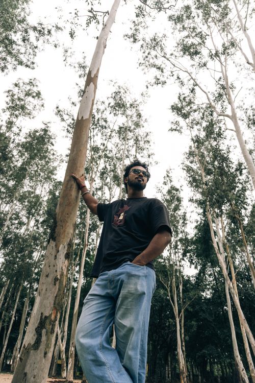 Free Outdoor scene with adult man among tall trees, looking contemplative, suggesting connection with nature. Stock Photo