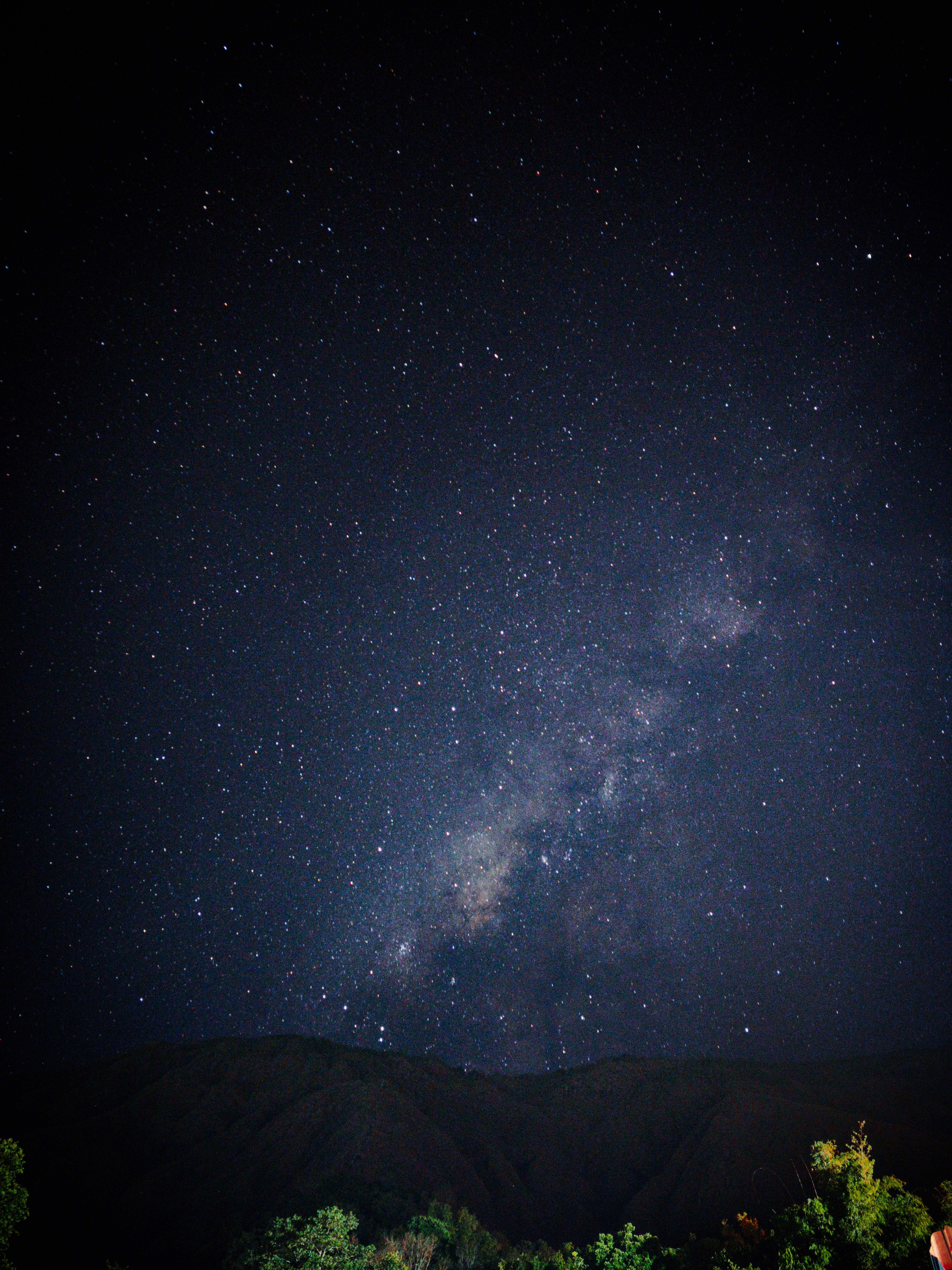 Fotomural Impresionante vista de la Vía Láctea brillando intensamente sobre las montañas durante una noche despejada.