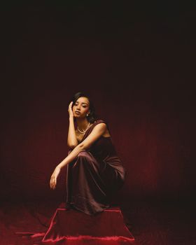 Sophisticated portrait of a woman sitting gracefully in a dark velvet dress.