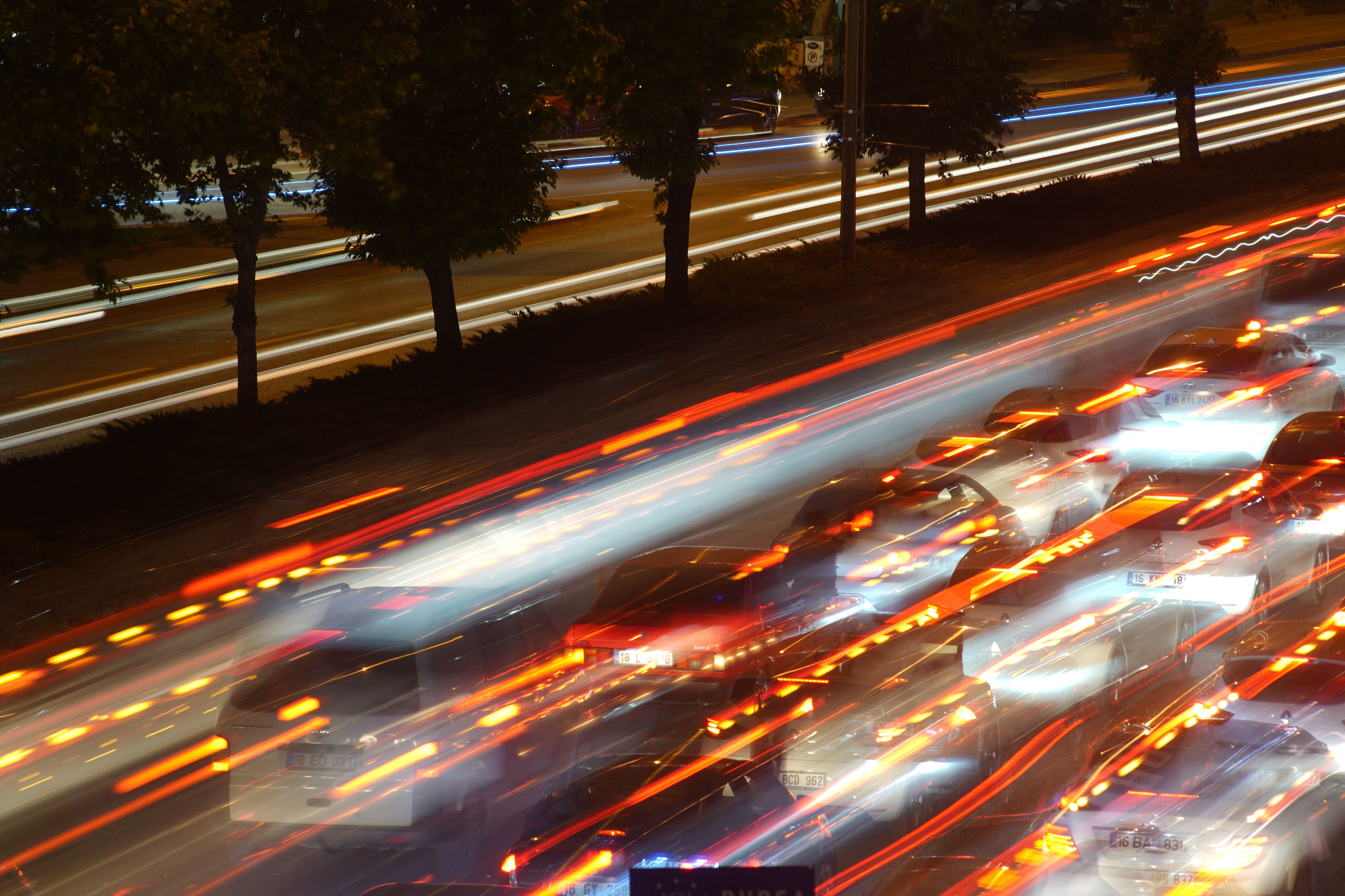 Busy city highway at night with colorful light trails from moving vehicles, capturing urban motion.