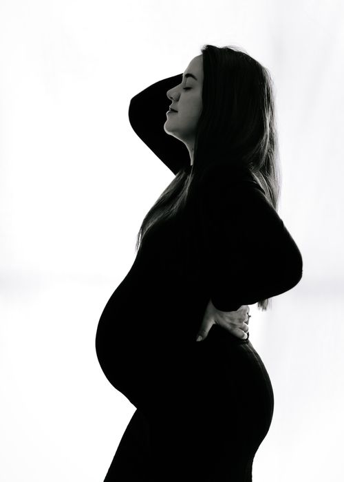 Free Elegant black and white silhouette of a pregnant woman posing indoors. Stock Photo