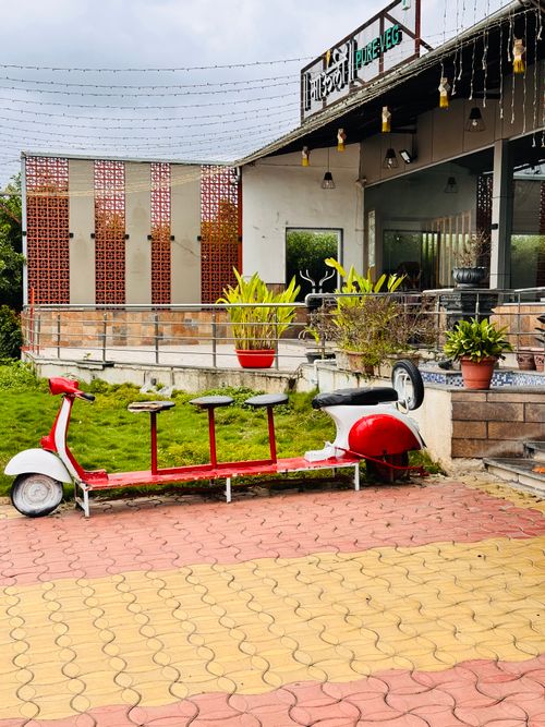 Free Creative outdoor cafe setting with unique red bicycle seating under string lights. Stock Photo